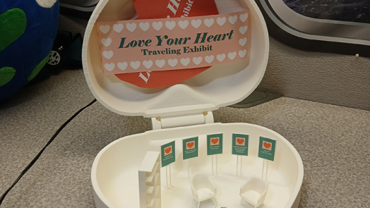 Miniature heart box with doll-sized furniture and posters inside.