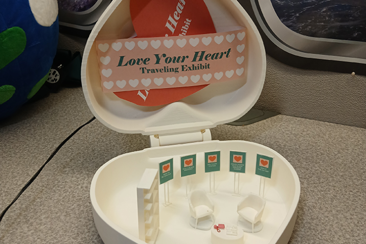 Miniature heart box with doll-sized furniture and posters inside.