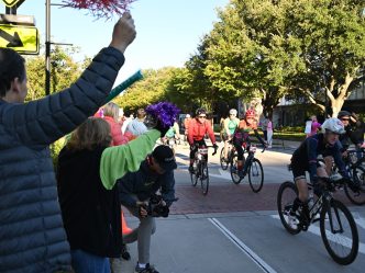 People are standing outside the Georgia Cancer Center's M. Bert Storey Research Building cheering and celebrating particpants taking part in PaceDay 2023.
