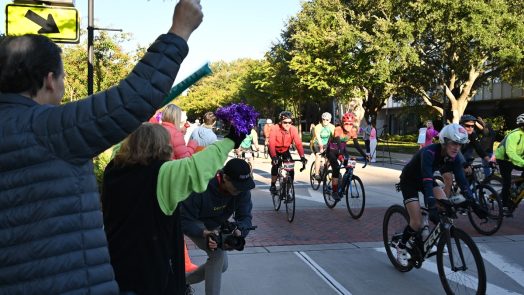 People are standing outside the Georgia Cancer Center's M. Bert Storey Research Building cheering and celebrating particpants taking part in PaceDay 2023.