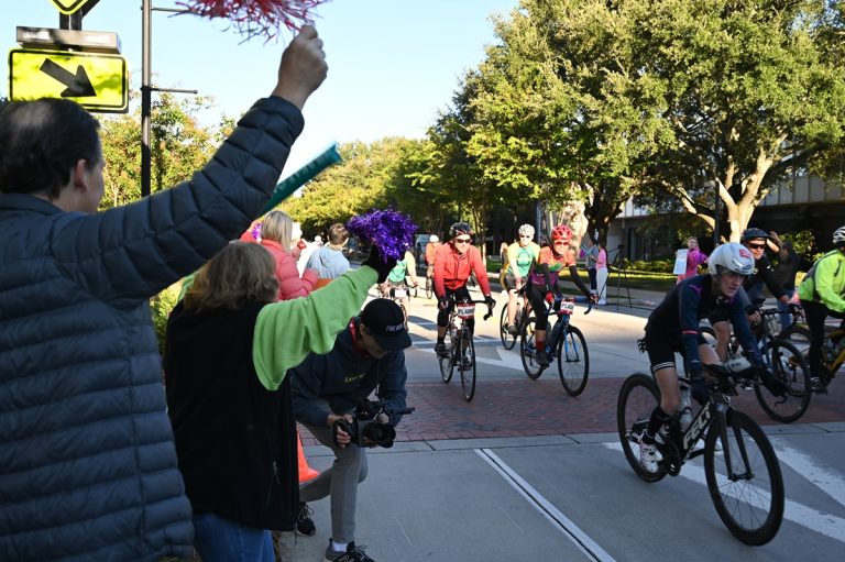 People are standing outside the Georgia Cancer Center's M. Bert Storey Research Building cheering and celebrating particpants taking part in PaceDay 2023.