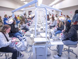 Students and adults sitting and participating in a dental hygiene simulation