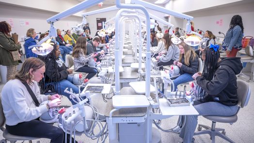 Students and adults sitting and participating in a dental hygiene simulation