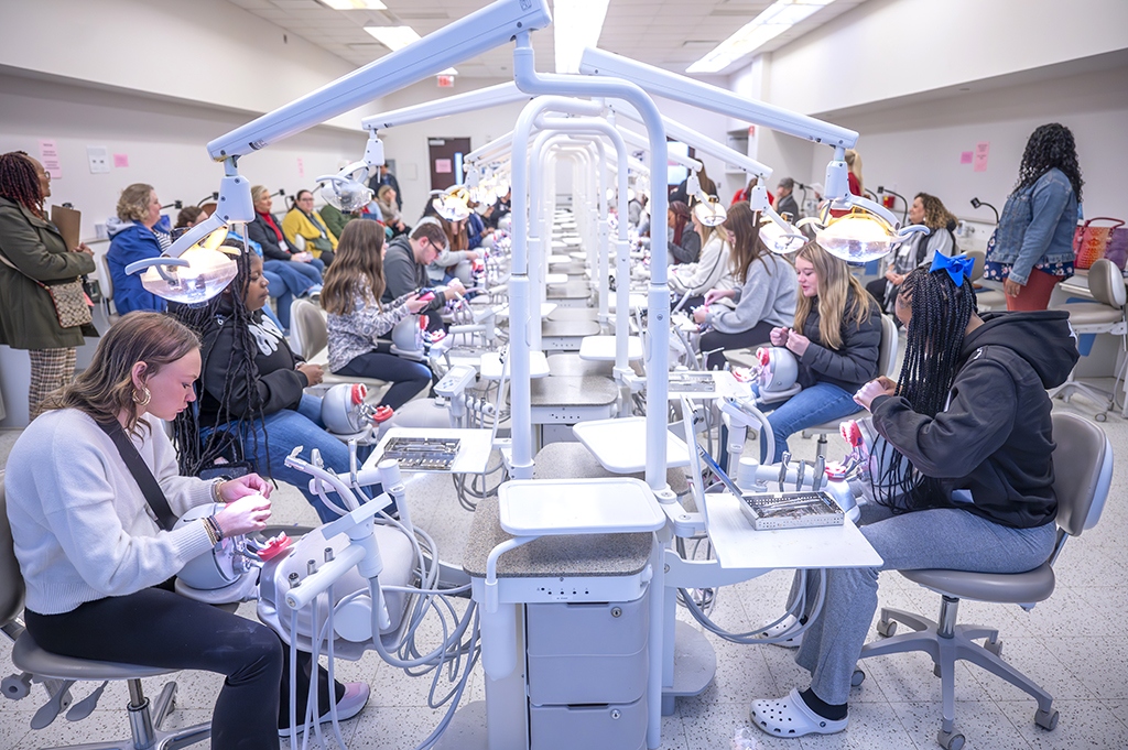 Students and adults sitting and participating in a dental hygiene simulation