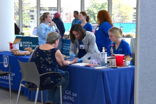 College nursing students conduct routine tests on an older patient.