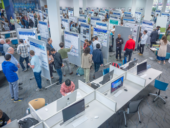 View from above looking down at young adults and visitors looking at large presentation boards in crowded room