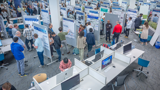 View from above looking down at young adults and visitors looking at large presentation boards in crowded room