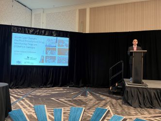 Man stands at a podium next to a presentation screen