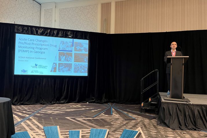 Man stands at a podium next to a presentation screen