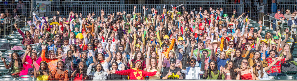 Large group of students in costume celebrate with hands in the air. [Michael Holahan/Augusta University]