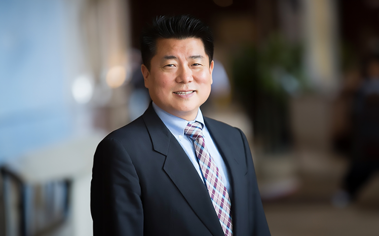 A man in a suit and tie stands in a hallway.