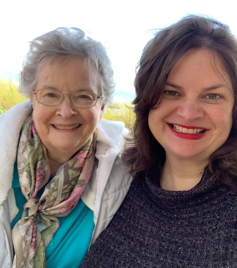 An elderly mother and her middle-aged daughter take a selfie.