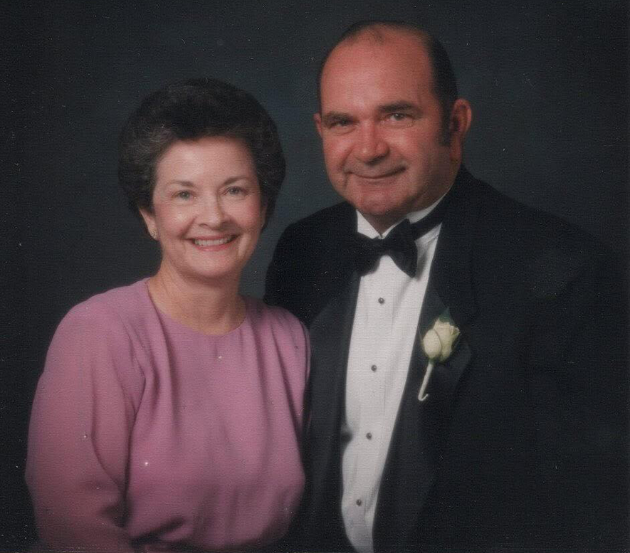 A woman and a man wearing a tux smile for the camera.