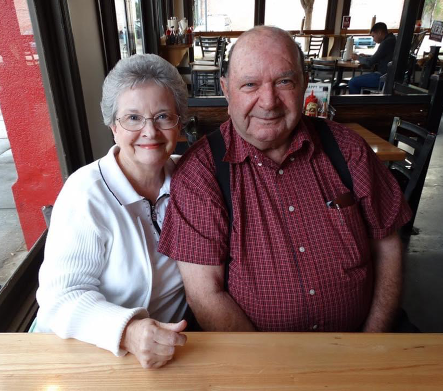 A woman and a man sitting at a table smile at the camera.
