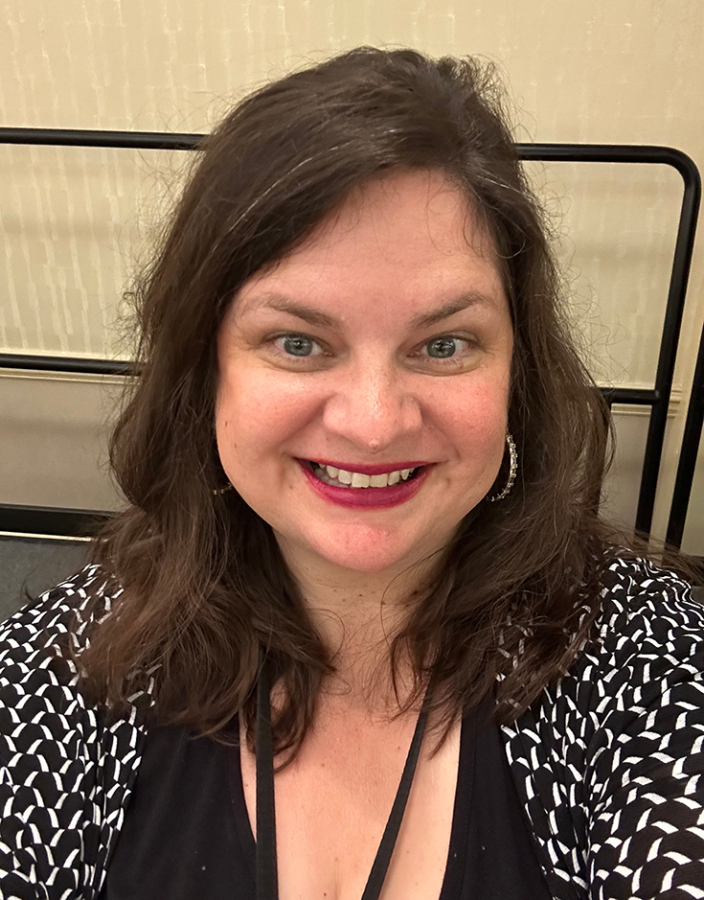 A smiling woman takes a selfie.