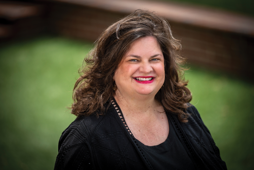 A well-dressed woman smiles at the camera.