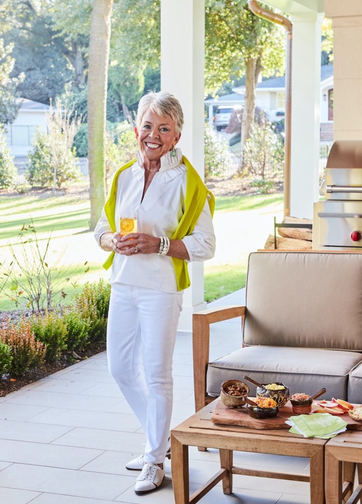 Woman standing on a porch holding a glass of sweet tea with a slice of lemon in it