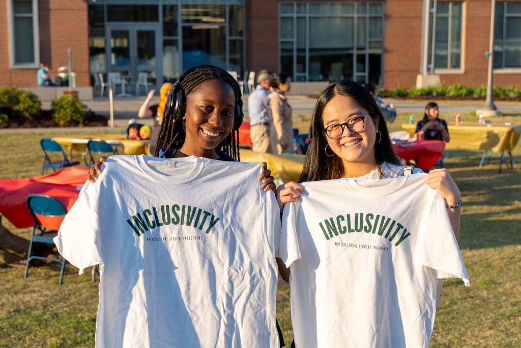 Two female students holding up T-shirts.