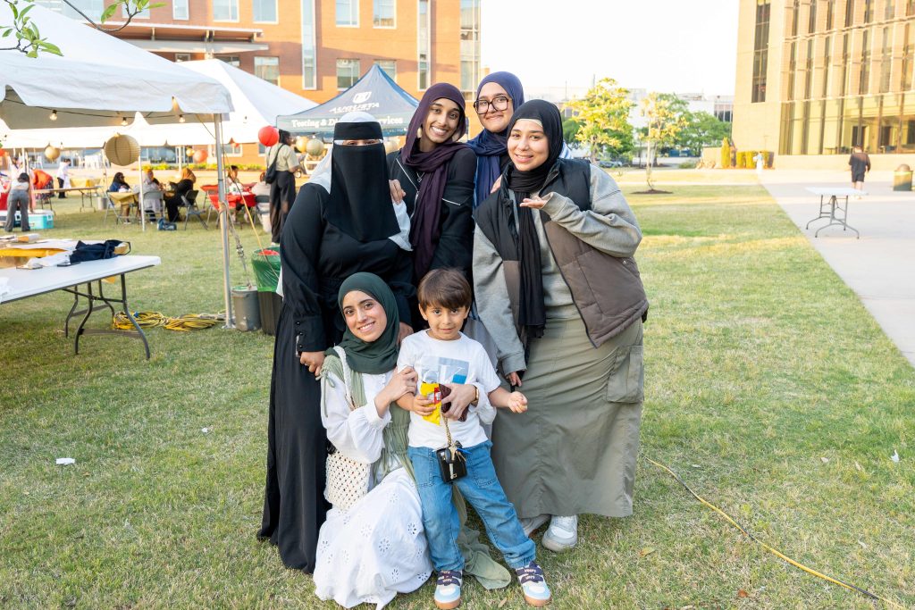 A group of women and a male child stand together in a group outdoors.