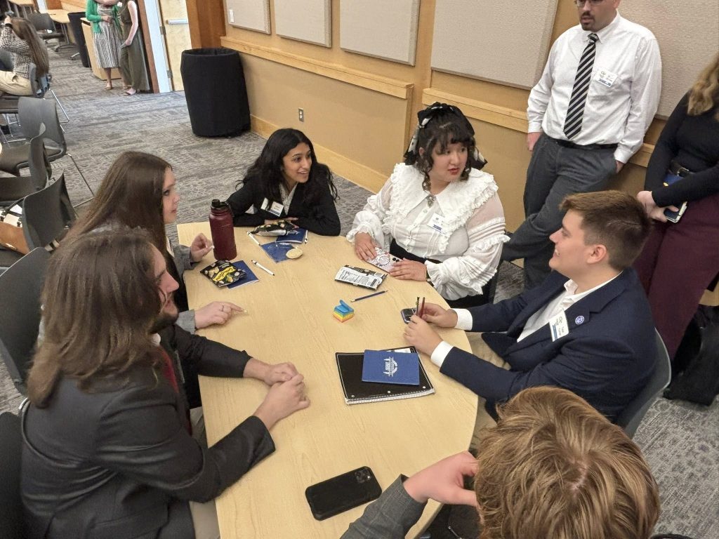 A group of college students sit around a table talking.