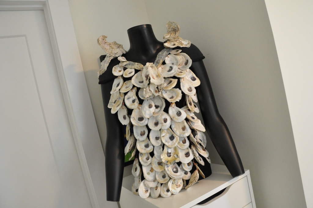A shirt made out of oyster shells rests on the upper torso of a mannequin