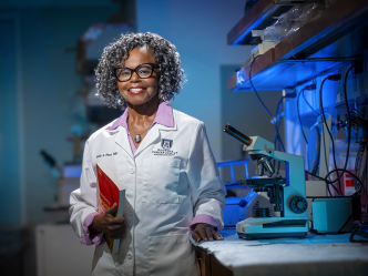 A woman wearing a lab coat stands in a scientific lab.