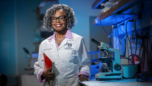A woman wearing a lab coat stands in a scientific lab.