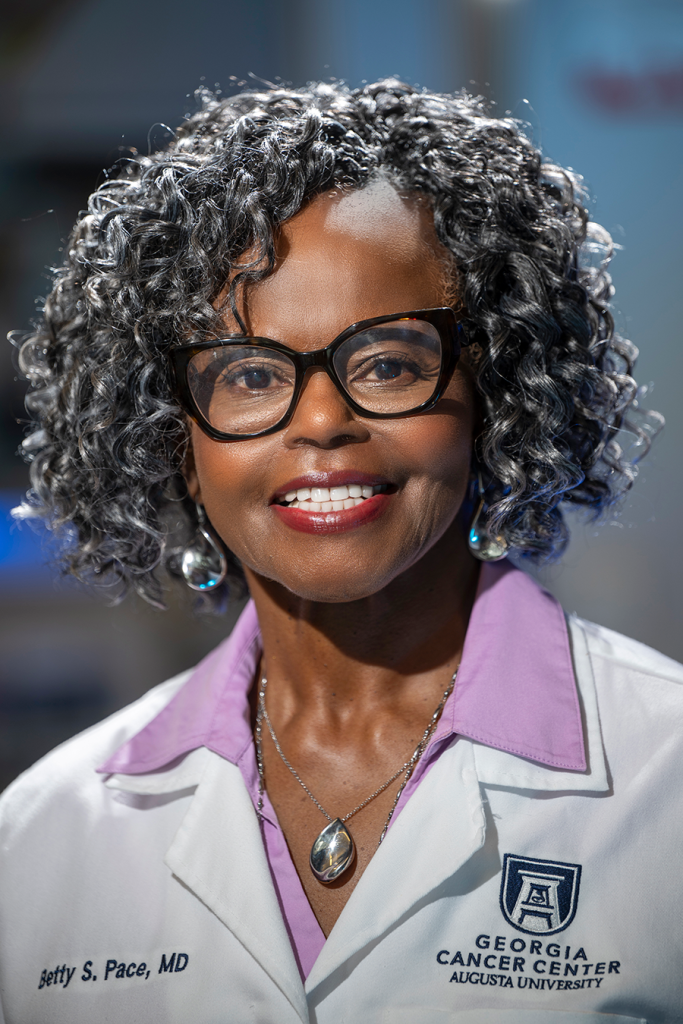 A woman in a scientific lab coat stands in a scientific lab.
