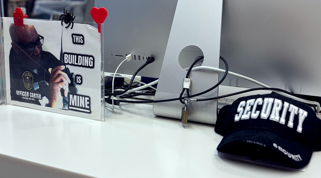 A framed photo of Carter with text that reads, "Officer Carter reporting for duty ... This building is mine" and hat that reads "Security" across it sit on Carter's desk.