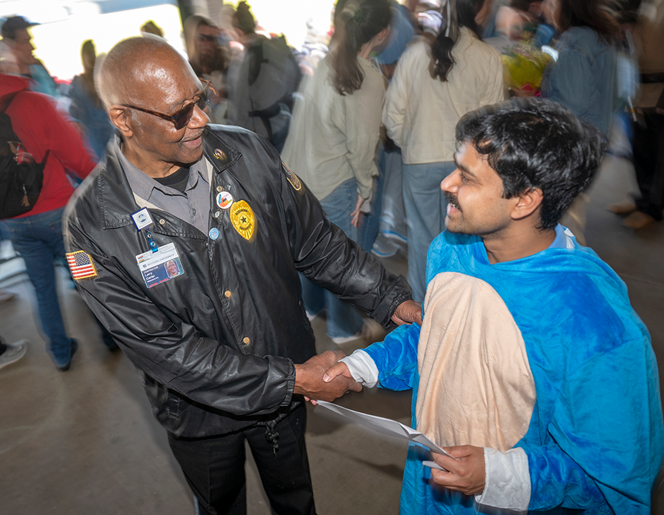 A medical college's security guard shakes the hand of a medical student wearing a character costume at Match Day.