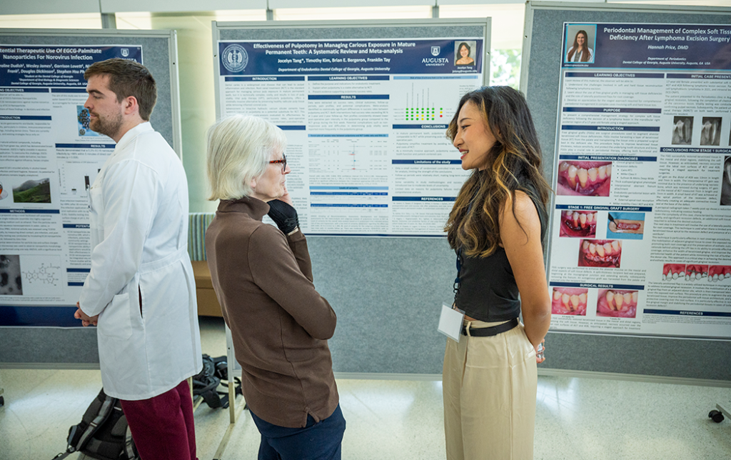 Two women, one a researcher, stand in front of a research presentation and talk.