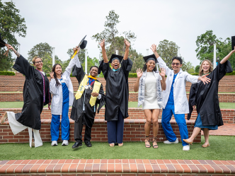 Five women and two men jump and raise their hands in celebration.