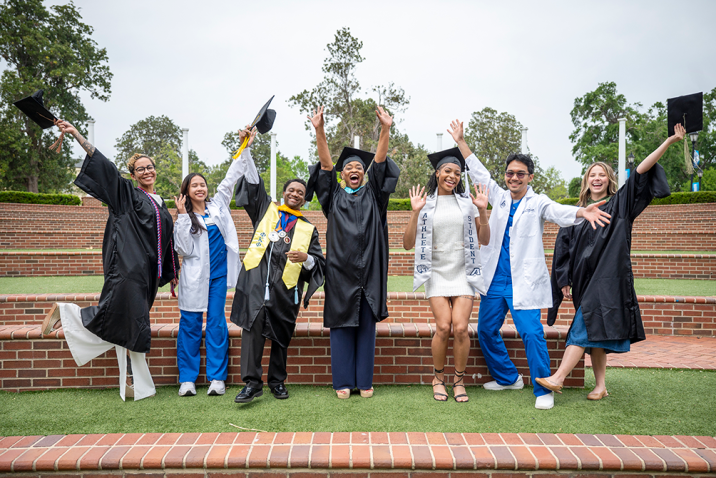 Five women and two men jump and raise their hands in celebration.