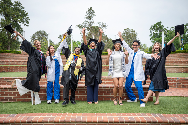 Five women and two men jump and raise their hands in celebration.