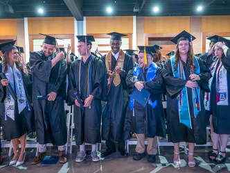 College graduates in caps and gowns celebrate turning their tassels from right to left to signify they have officially graduated.