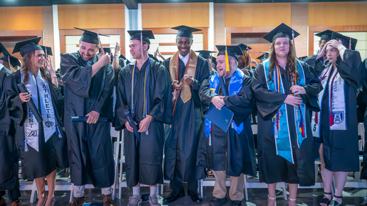 College graduates in caps and gowns celebrate turning their tassels from right to left to signify they have officially graduated.