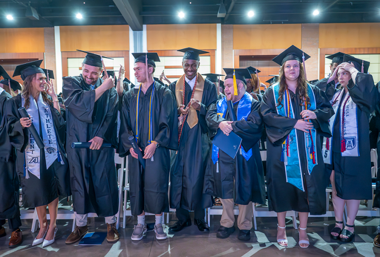College graduates in caps and gowns celebrate turning their tassels from right to left to signify they have officially graduated.