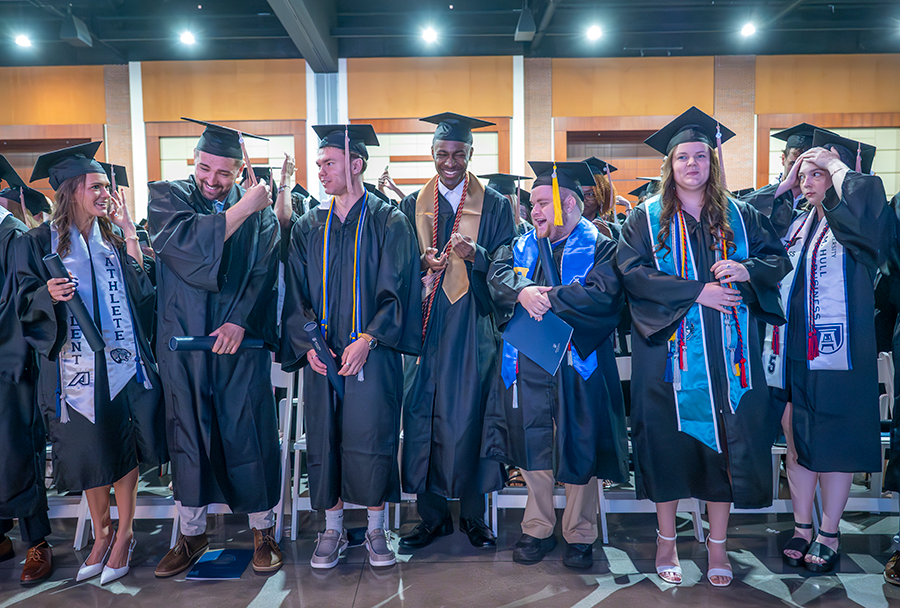 College graduates in caps and gowns celebrate turning their tassels from right to left to signify they have officially graduated.