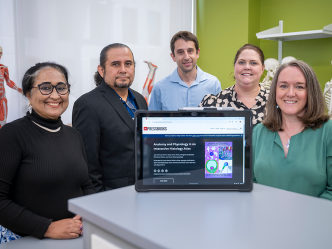 Five college professors pose behind an iPad showing an online histology textbook.