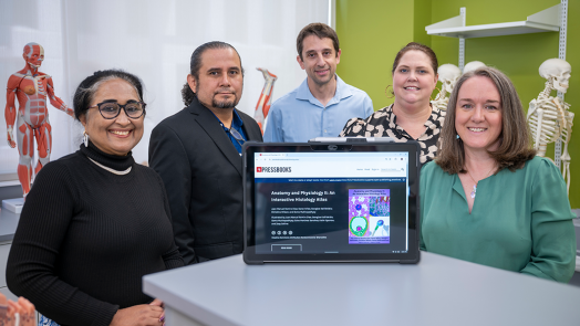 Five college professors pose behind an iPad showing an online histology textbook.