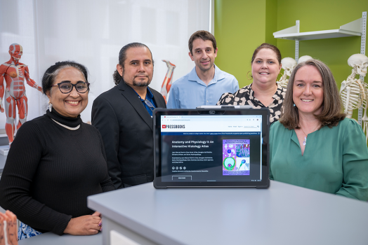 Five college professors pose behind an iPad showing an online histology textbook.