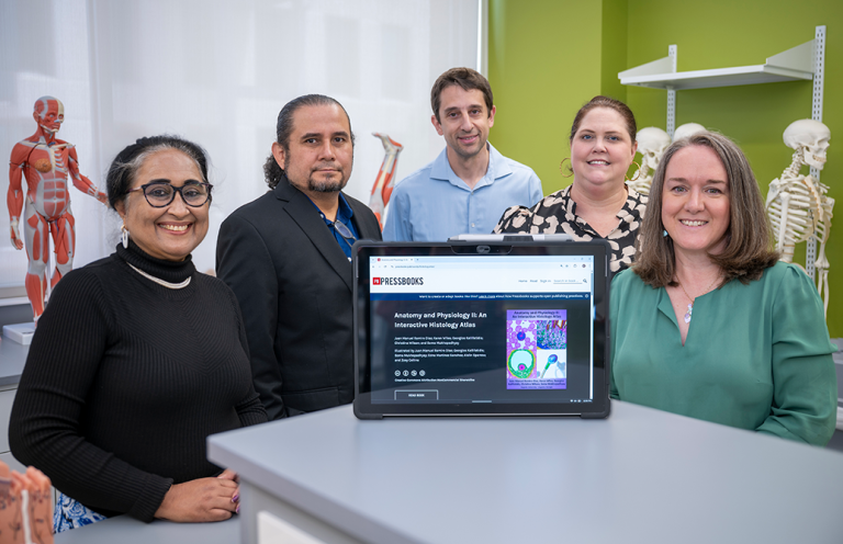 Five college professors pose behind an iPad showing an online histology textbook.