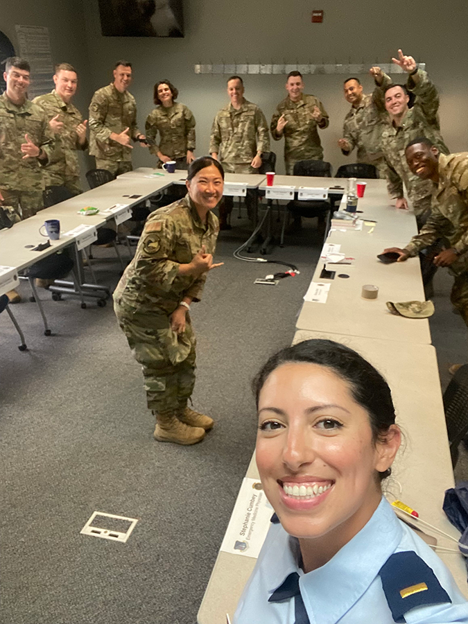 A military officer takes a photo with a room full of fellow soldiers.