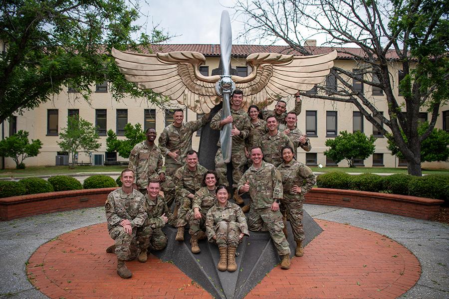A group of soldiers gather around a large statue after completing a rigorous course.