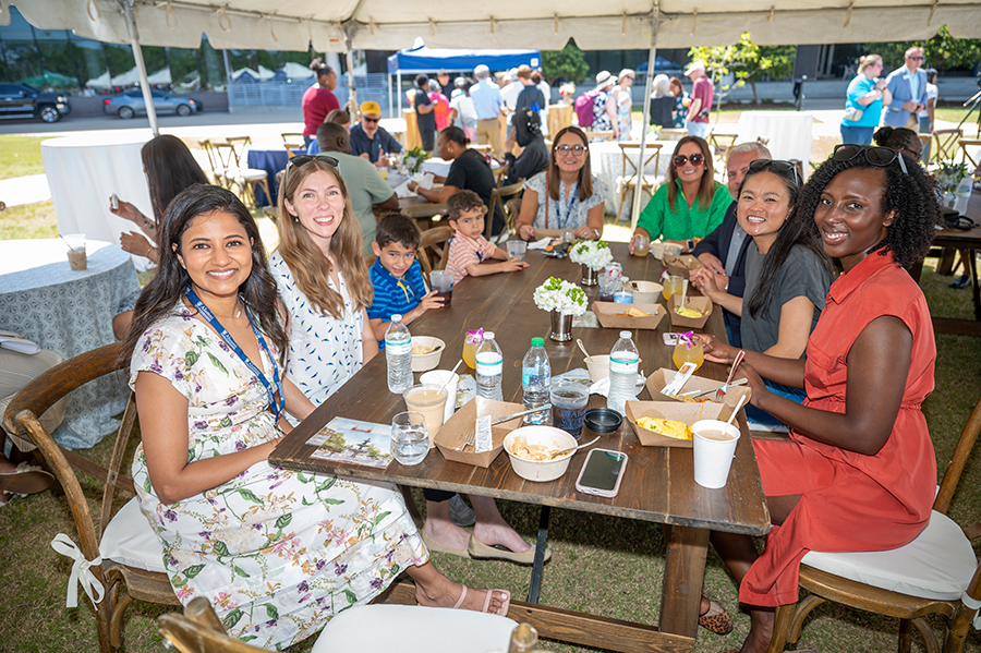 A group of women sit around a table under a large tent during a big event.