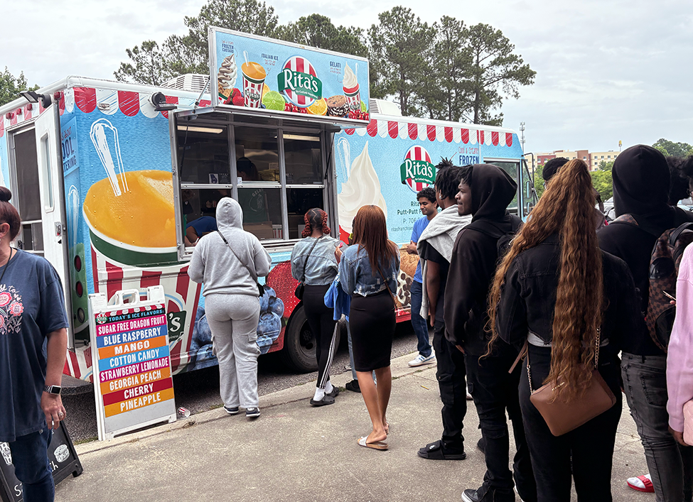 High school students waiting in line to order from a Rita's Italian ice and frozen custard truck.
