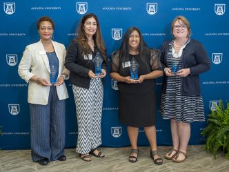 Four women smiling while holding awards