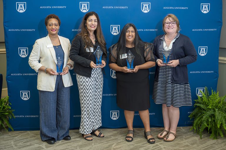 Four women smiling while holding awards