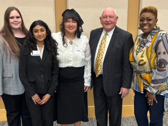 Three college students stand with an older man and a female faculty member.