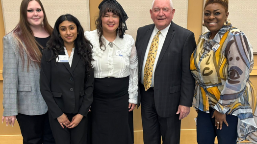 Three college students stand with an older man and a female faculty member.